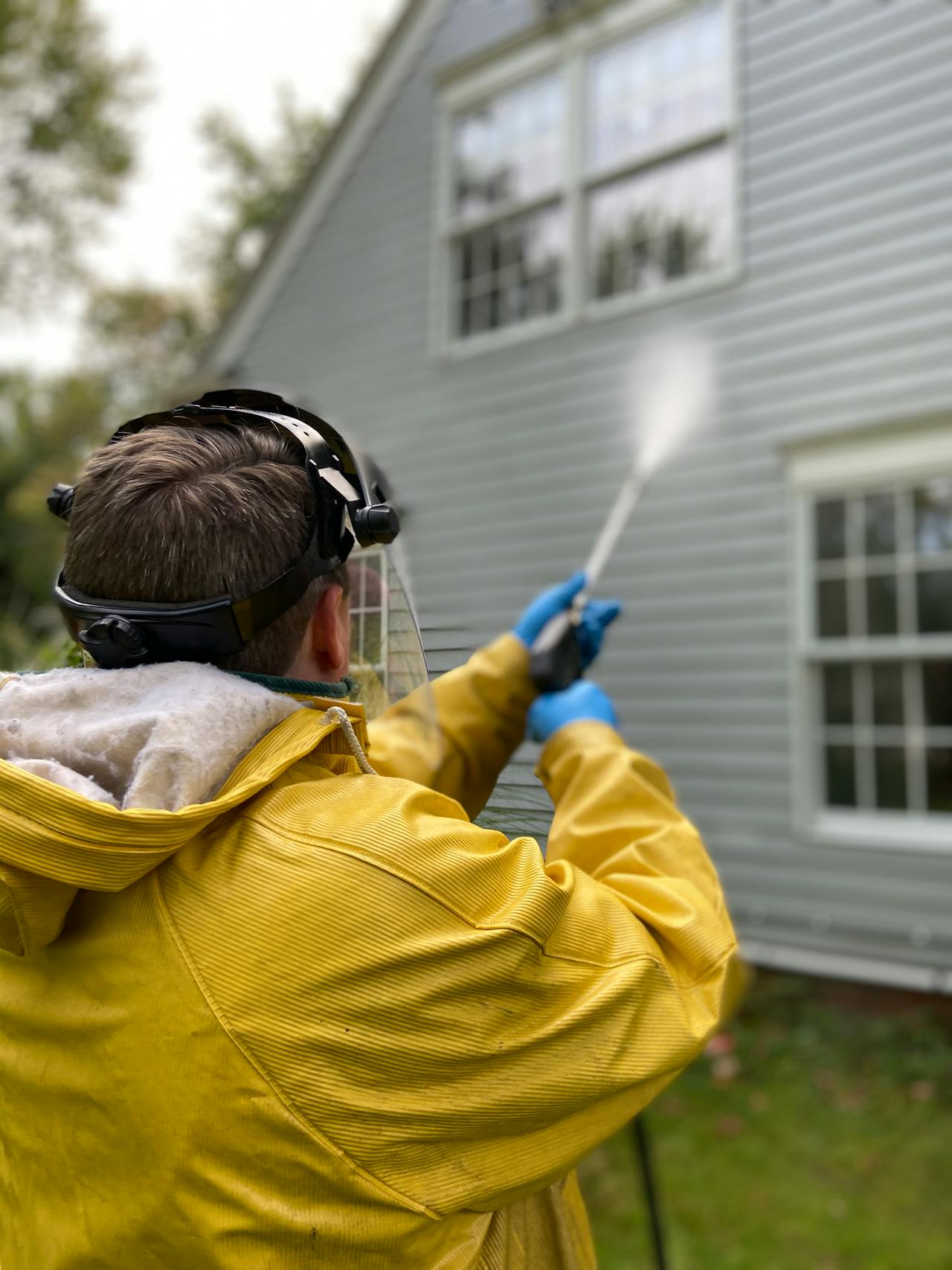 Person pressure washing exterior of a house